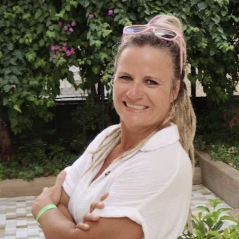 Mandy Mehring Junge Frau mit langen, braunen Haaren, lächelt in einer urbanen Umgebung.