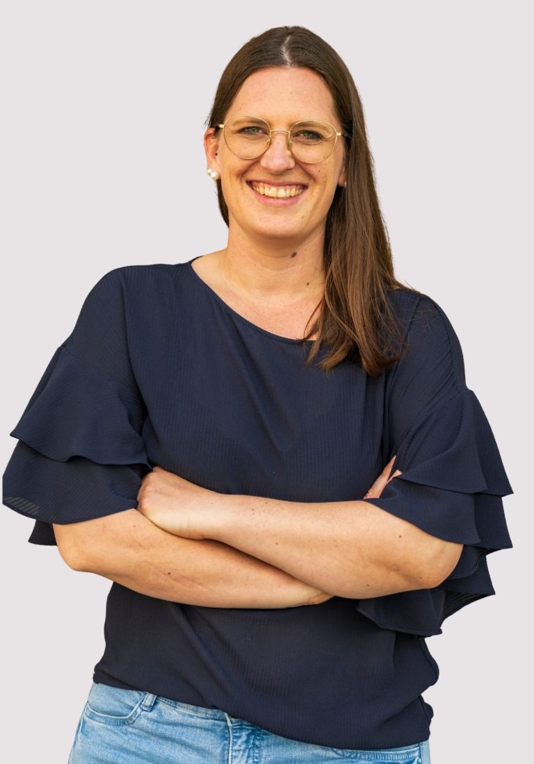 Kathrin Heimburger Lächelnde Frau mit lässiger Kleidung, Arme vor der Brust verschränkt.